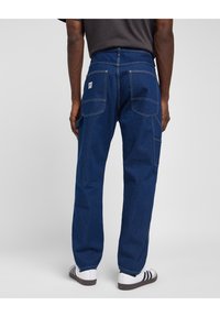 Dark blue denim pants with a straight fit, featured back pockets, contrasting stitching, and a small brand label on the waistband.