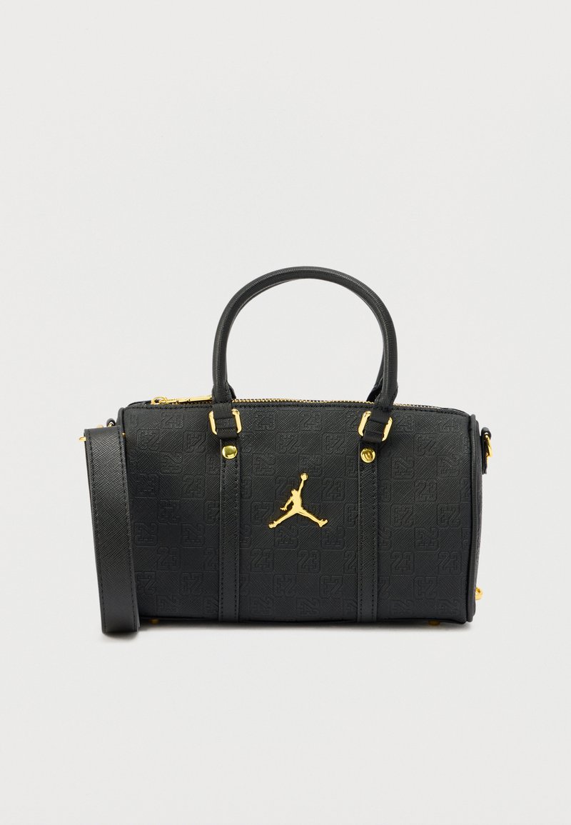 Musta teksturoidusta materiaalista valmistettu käsilaukku, jossa on vetoketjusuljin, kullanväriset yksityiskohdat ja näkyvä Jumpman-logo edessä.