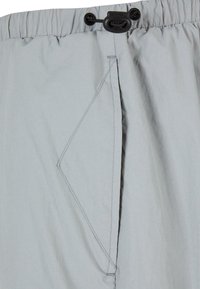 Jasnoszare szorty wykonane z lekkiego materiału. Posiadają elastyczną talię ze sznurkiem do ściągania oraz ukośną kieszeń boczną.