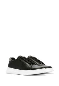 Baskets en cuir noir avec une finition lisse, semelles en caoutchouc blanc et lacets noirs. Présentent une touche de gris au niveau du talon.