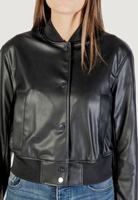 Giacca bomber nera in pelle con colletto a costine, bottoni a pressione e tasche frontali. Design aderente con una texture liscia e lunghezza crop.