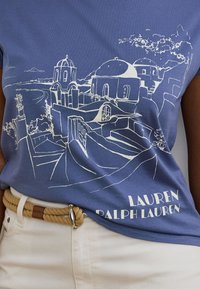 Μπλε βαμβακερό t-shirt με λευκό σκίτσο ενός παράκτιου χωριού με θόλους στις στέγες και αρχιτεκτονικές λεπτομέρειες, με την επιγραφή "Lauren Ralph Lauren."