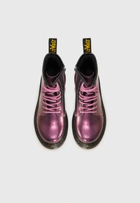 Stivaletti alla caviglia in pelle metallica viola con lacci rosa e un pannello testurizzato nero. Presentano un'etichetta gialla e una suola nera spessa.