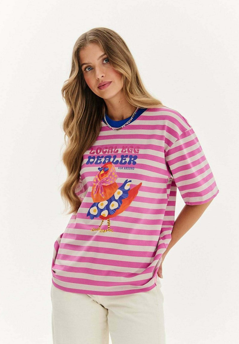 Pruhované růžové tričko s barevnou grafikou ptáka a textem "MÍSTNÍ PRODEJCE VEJEC." Měkká tkanina, volný střih a krátké rukávy.