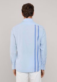 Camisa de manga larga azul claro con un diseño de rayas verticales en contraste en varios tonos de azul. Confeccionada en tela suave, cuenta con cuello y botones.
