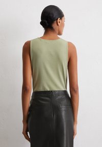 Light green sleeveless top paired with a black leather pencil skirt. The top is smooth, while the skirt has a sleek, textured finish.