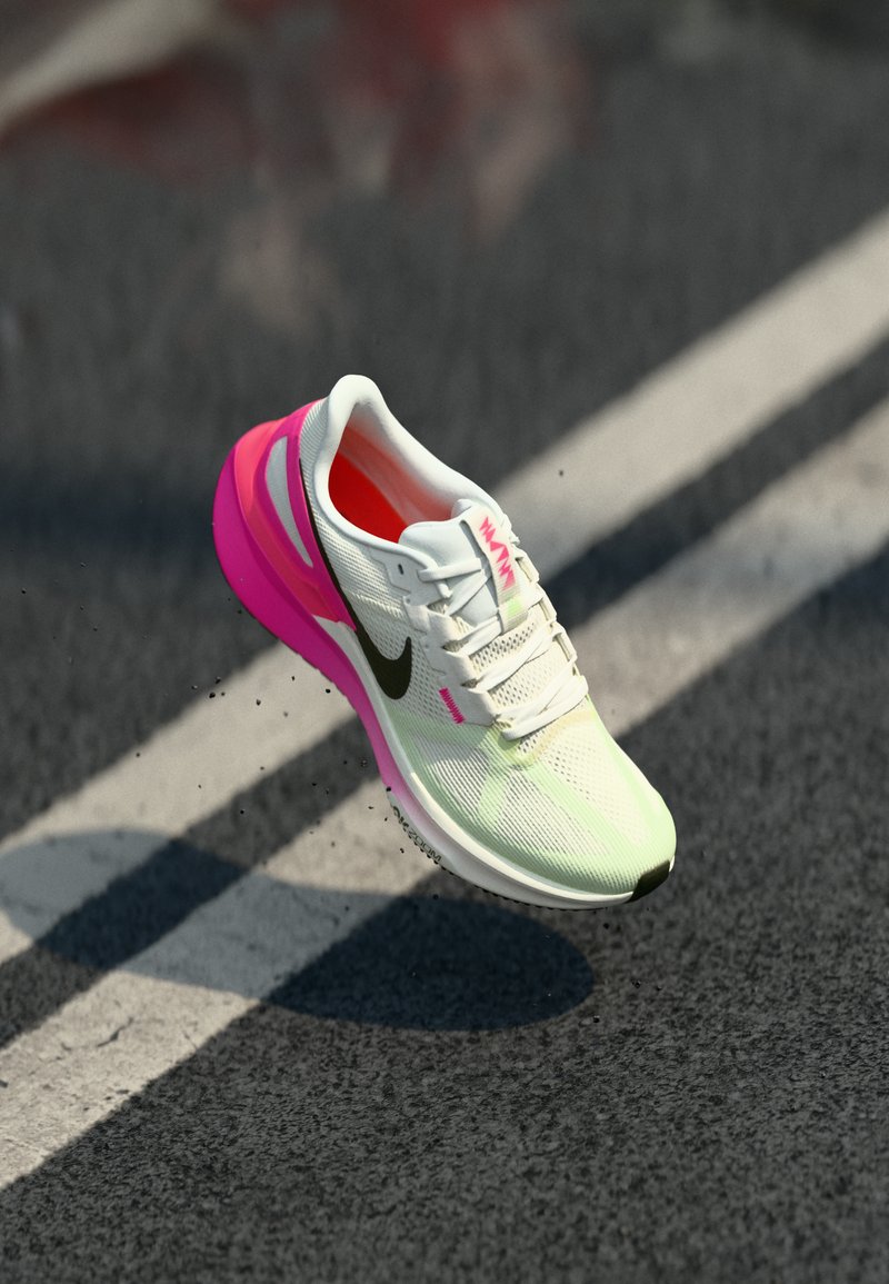 Chaussure de sport blanche et rose avec une tige en mesh respirant, logo noir et un talon chunky rose. Présente des matériaux texturés et un laçage.