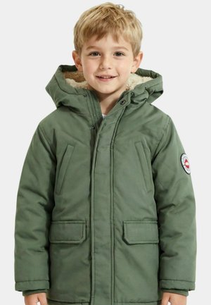 Jeune garçon souriant aux cheveux blonds courts, portant une veste d'hiver verte à capuche avec doublure en polaire et poches avant.
