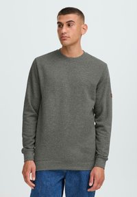 Grå genser med rund hals laget av myk stoff, med lange ermer og ribbet kant, med et lite logo-lapp på ermet.