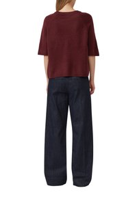 Haut tricot à manches courtes bordeaux avec un col côtelé, associé à un pantalon en denim foncé à jambes larges, présentant une coupe classique et une texture lisse.