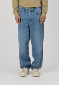 Denim hlače v svetlo modrem pranju, z ohlapnim krojem, petimi žepi in vidnim šivom po nogah. V kombinaciji z belimi supergami.