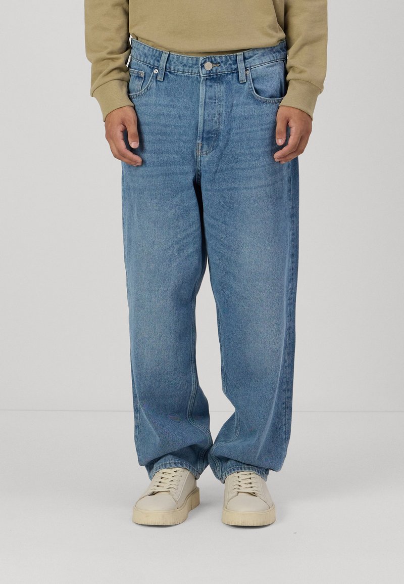 Denim hlače v svetlo modrem pranju, z ohlapnim krojem, petimi žepi in vidnim šivom po nogah. V kombinaciji z belimi supergami.