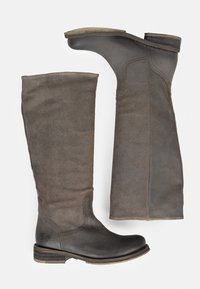 Botas altas de ante marrón con puntera de cuero suave, tacón de madera apilada y detalle de costura lateral. El diseño presenta una estética minimalista.