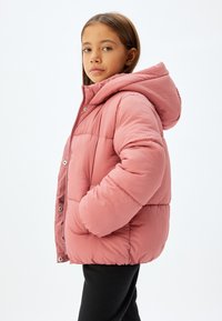 Vatteret jakke i blød lyserød, med hætte, lynlåslukning og sidelommer. Tekstureret materiale med sømdetaljer for varme.