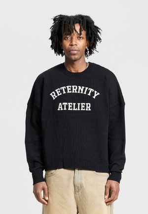 Black knit sweatshirt featuring white "RETERNITY ATELIER" text across the chest, oversized fit, ribbed cuffs, and hem.
