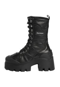 Stivali da combattimento neri con lacci, realizzati in pelle texturizzata, suola in gomma chunky e patch con logo. Presentano occhielli metallici e un design alto fino alla caviglia.