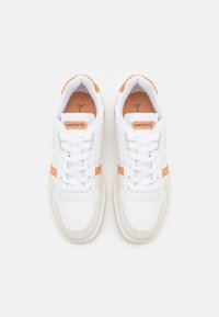 Sneakers bianchi con accenti arancioni. Realizzati in materiali lisci e testurizzati, con un design con lacci e una soletta imbottita.