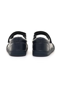 Zapatos de cuero negro con forma redondeada, con una correa en la parte trasera y textura suave. Suela de goma con un dibujo mínimo para mayor agarre.