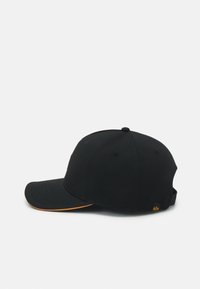 Čierna baseballová čiapka s zakriveným okrajom, ktorý má oranžový lem a malú logo nálepku na zadnom popruhu, umiestnená na bielom pozadí.