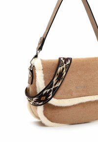 Sac à épaule en daim beige avec bordure en fausse fourrure blanche et bandoulière en tissu à motifs amovible à côté d'une bandoulière en cuir beige uni.