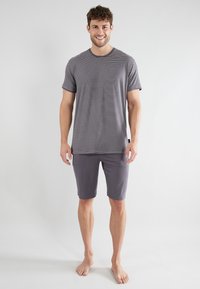 Grau gestreiftes T-Shirt mit kurzen Ärmeln, kombiniert mit grauen Shorts. Der Stoff wirkt weich; das Shirt hat horizontale Streifen und einen runden Halsausschnitt.