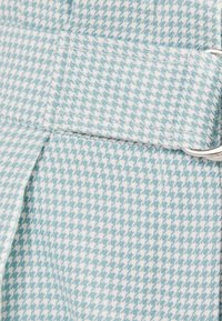 Tkanina s hladkou texturou v světle modrém a bílém vzoru pepito, s bočním popruhem se stříbrným kováním a pečlivými šicími detaily.