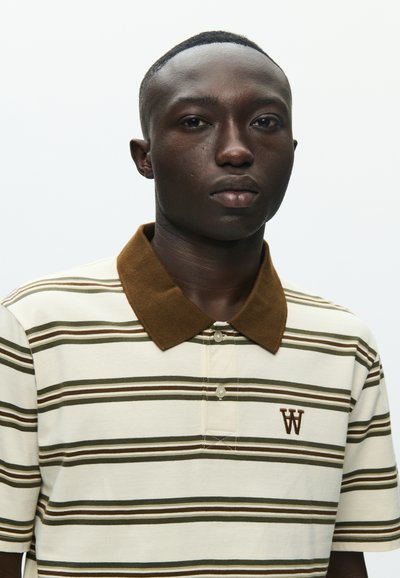Polo en tissu crème avec des rayures horizontales marron et vertes, un col marron et un petit logo brodé 'W'.