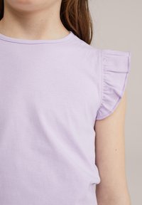 Violetinė trumpa rankovė viršūnė su raukiniais ant pečių, pagaminta iš minkštos medvilnės, su apvaliu iškirpimu ir vienoda tekstūra.
