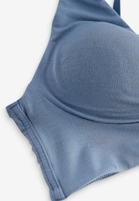 Svijetloplava grudnjak od glatkog, rastezljivog materijala, s okruglim šalicama, podesivim trakama i šavovima duž rubova.