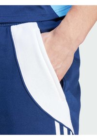 Marineblå sports shorts med hvid kant på lommen, med elastisk talje og sidelomme. Glat stof og subtil tekstur.