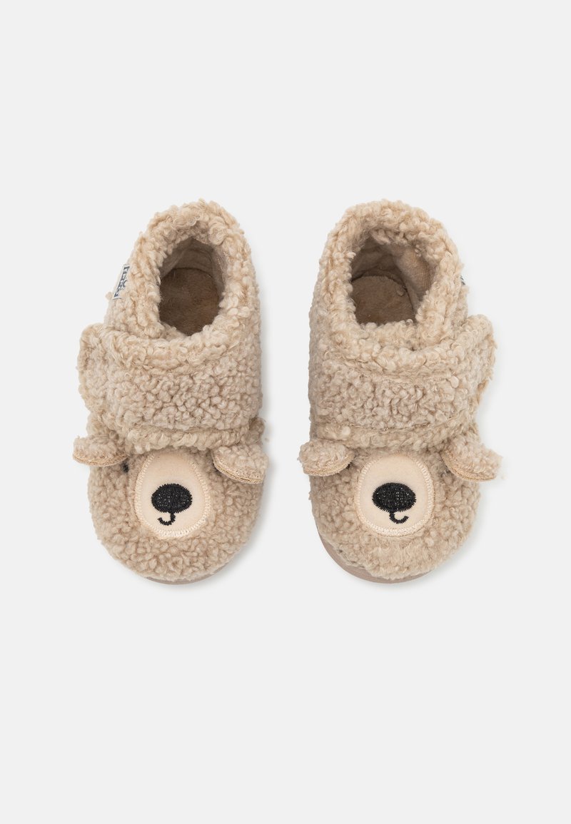 Chaussons en polaire beige avec une surface texturée, présentant un design de visage d'ours sur le bout, des accents d'oreilles douces, et un intérieur rembourré.