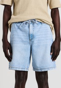 Helle blaue Denim-Shorts mit lockerem Schnitt, ausgestattet mit einem Kordelzugbund, Seitentaschen und Kontrastnähten entlang des Saums.