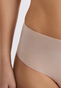 Sous-vêtements taille haute beige clair avec une texture lisse, un design sans coutures et une large ceinture pour le confort et la couverture.