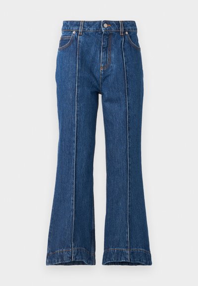 High-waisted denim flared jeans in dark blue with contrasting orange stitching, featuring a button closure and wide leg openings.