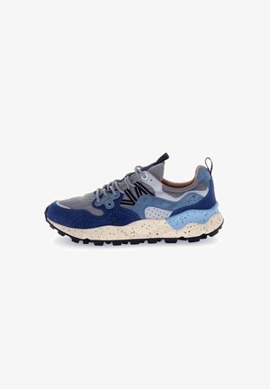 Zapatilla con paneles de ante azul marino, gris y azul claro, suela crema moteada y suela exterior de goma negra gruesa. Presenta cordones y detalles grises.