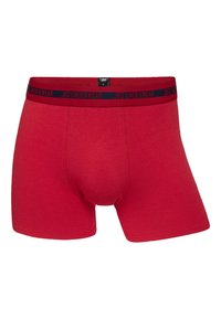Red cotton boxer briefs with a navy elastic waistband featuring "JBS UNDERWEAR" in contrasting lettering. Smooth texture and fitted design.