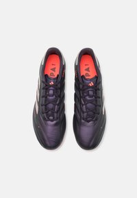 Le scarpe da calcio nere e rosse presentano una tomaia sintetica liscia, design con lacci e tre strisce bianche sui lati. Punta testurizzata.