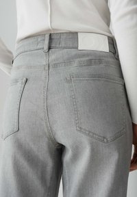 I jeans in denim grigio presentano un design aderente, uno stile a cinque tasche e un'etichetta bianca alla vita con marchio impresso.