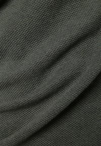 Gros plan sur un tissu tricoté gris foncé texturé avec de petites boucles étroitement tissées et des plis doux.