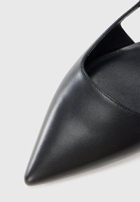 Μαύρο δερμάτινο παπούτσι μυτερό με κομψό σχέδιο, που διαθέτει ανοιχτό πλαϊνό άνοιγμα και λεία, γυαλιστερή επιφάνεια.