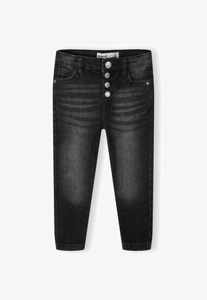 Mustadest denimist valmistatud kitsad teksad, kõrge vöökoht, viis taskut ja nupuvajutusega pikendatud lukuga, milles on kolm metallist nuppu. Ees on kerge pleekimine.