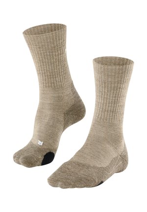 Paire de chaussettes beige longueur mollet avec bords côtelés et sections renforcées au talon et aux orteils de couleur noire.