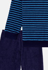 Navy blue striped sweater with light blue horizontal stripes, paired with solid navy blue plush lounge pants. Soft, textured fabric.
