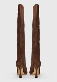 Brown suede over-the-knee boots with a fitted design. Thin pointed heels and a smooth texture. No visible hardware or additional accents.