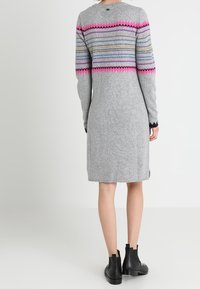 Graues Strickkleid mit langen Ärmeln, das oben am Rücken mehrfarbige Zickzackmuster in Pink, Blau und Beige zeigt.