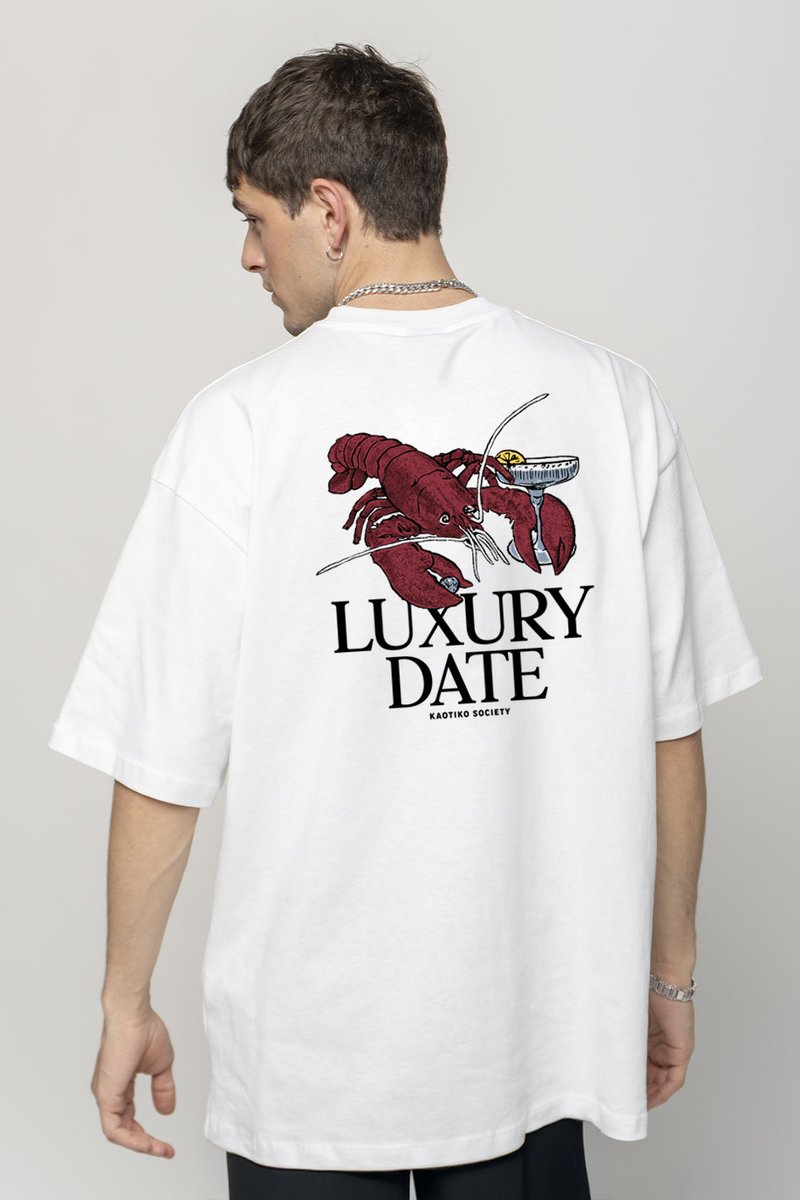 Camiseta blanca de gran tamaño con un gráfico de dos langostas rojas y un vaso de cóctel, con el texto "CITA DE LUJO" debajo en negrita negra.