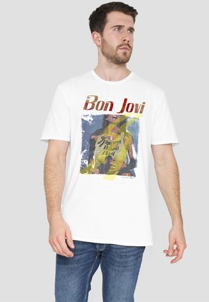White t-shirt featuring a graphic print of a woman in a yellow outfit with "Bon Jovi" text and "Slippery When Wet" in bold lettering.