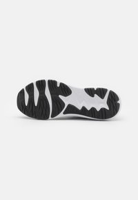 Semelle de chaussure avec un motif de traction en caoutchouc noir sur fond blanc, présentant un design ondulé et une surface texturée pour une meilleure adhérence et stabilité.