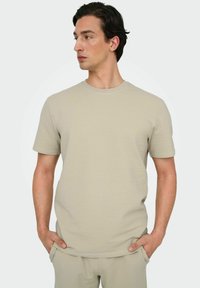 Beige tekstureret t-shirt med rund hals og korte ærmer, lavet af et blødt materiale, designet med en afslappet pasform.