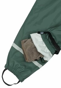 Gröna vattentäta byxor med åtstramad ankel och reflexsilver rand, med ett brunt fleecfoder och en vit fickinsats.
